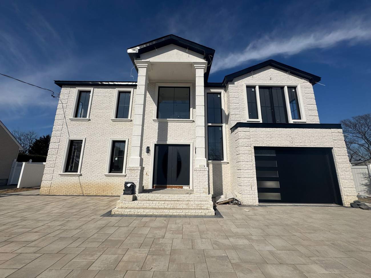 White brick colonial-style new construction with columned entry