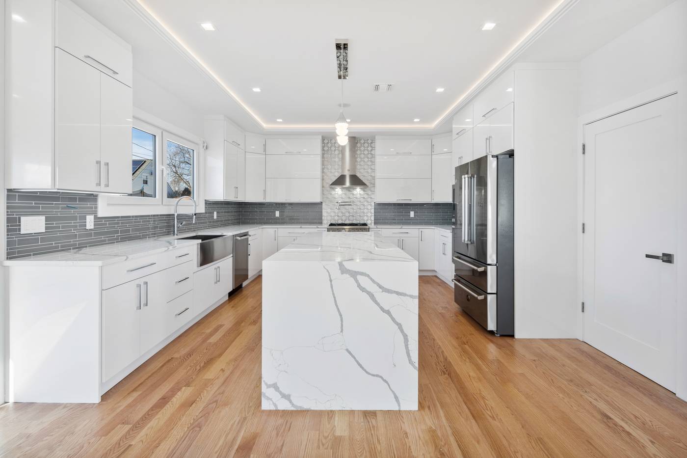 White kitchen with waterfall quartz island and oak floors