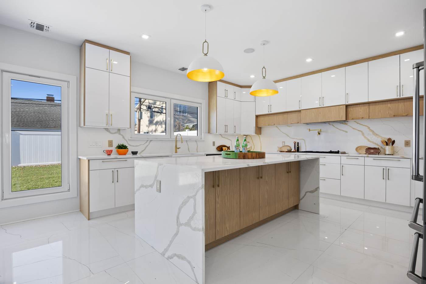 White and oak kitchen with gold dome pendants and calacatta slab backsplash