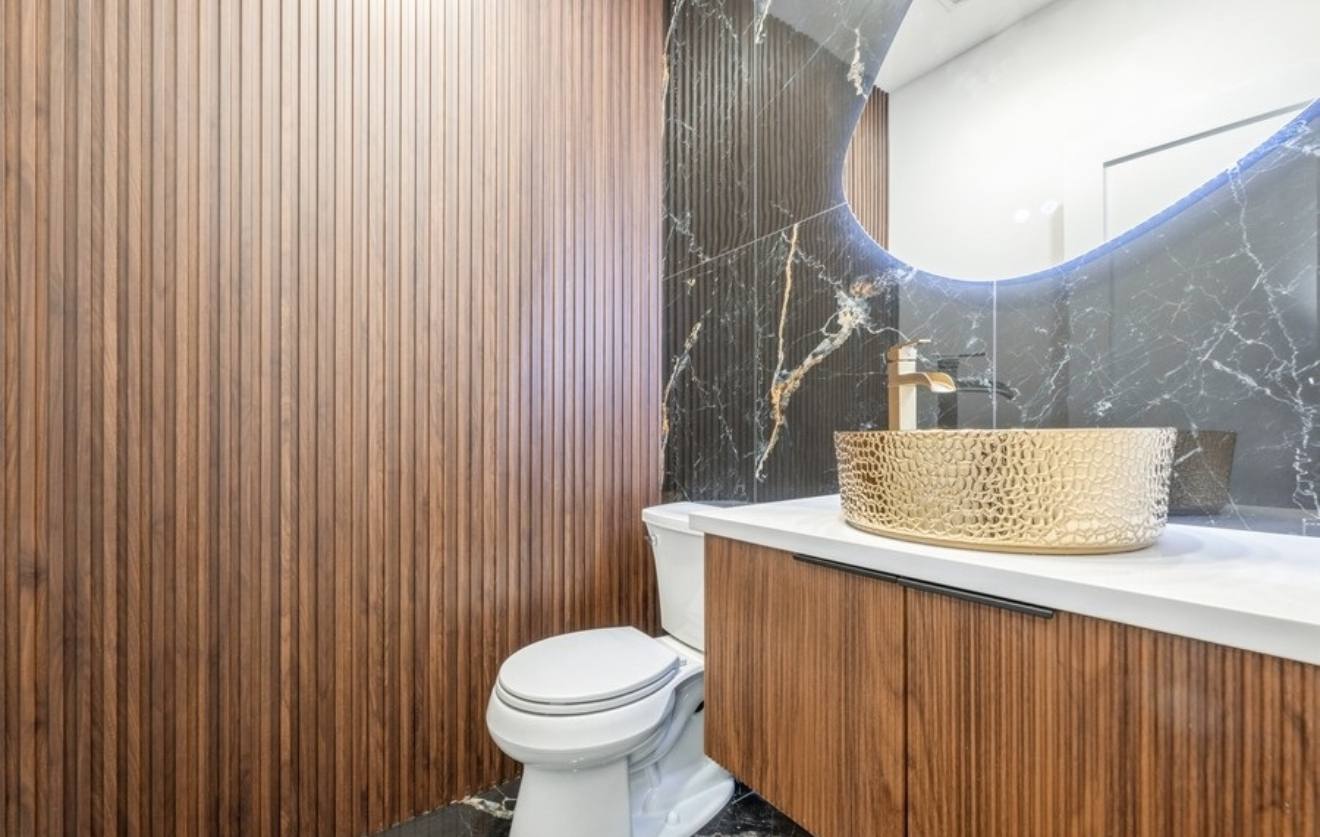 Powder room with walnut slat wall, black marble and gold vessel sink